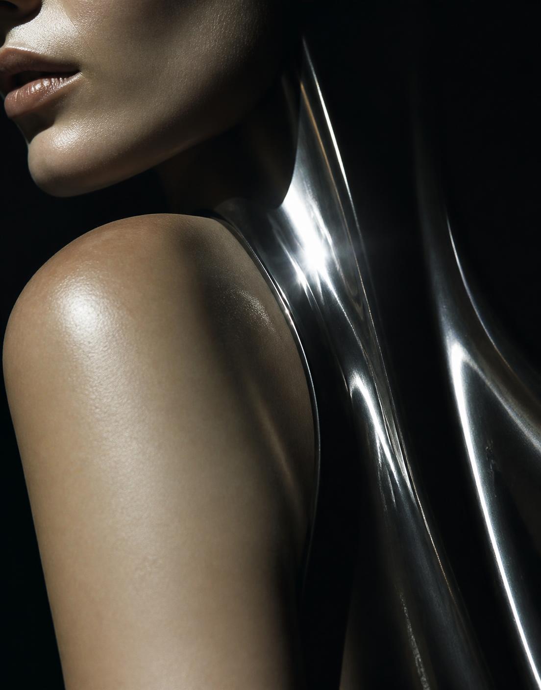 Editorial study: bare shoulder and jaw against a curved sheet of liquid chrome